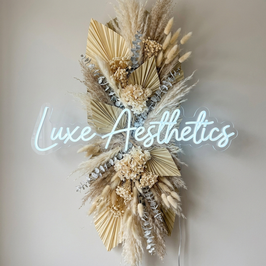 LED-Neon-Logo „Luxe Aesthetics“ über Pampasgras im Ästhetik-Studio – Neon Atelier