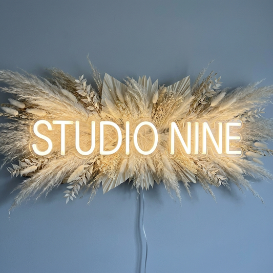 LED-Neon-Logo „Studio Nine“ über Pampasgras im Beautystudio – Neon Atelier