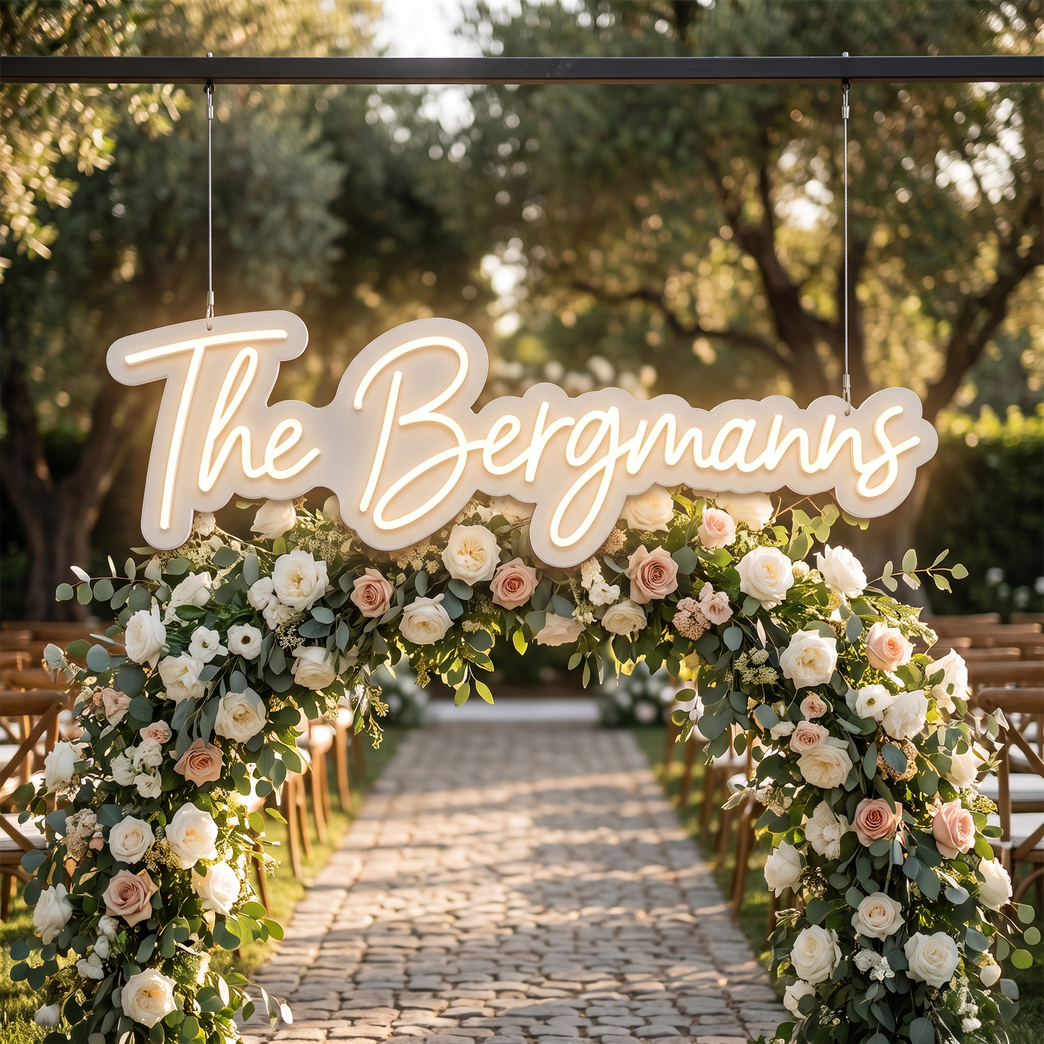 LED-Neonschild „The Bergmanns“ an einem Blumenwand-Bogen bei der Hochzeit – Neon Atelier