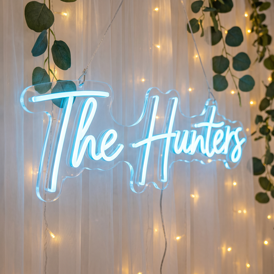 LED-Neonschild „The Hunters“ vor einem Vorhang in Nahaufnahme – Neon Atelier